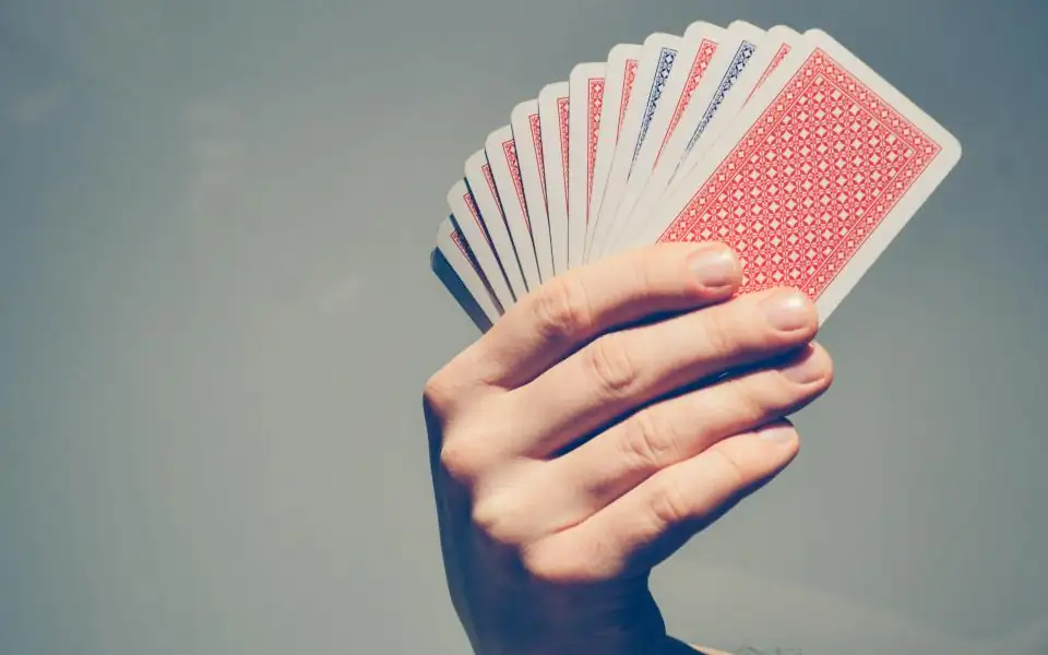 Hand holding playing cards for tongits and card games on 218PLUSPH